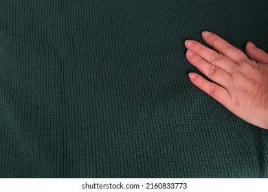 close-up of female hand touches knitted jersey, embossed canvas, green wool yarn, knitted texture, concept of warm things for cold weather, check quality, fashionable clothes, clothing production