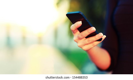 Closeup Of Female Hand Using A Smart Phone. Shallow Depth Of Field