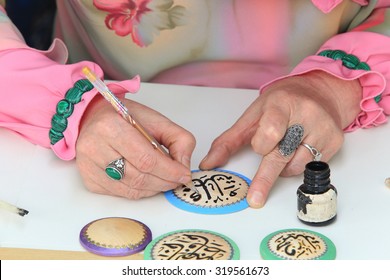 Close-up Of Female Hands Artist In Tatar National Costume, Making Arabic Calligraphy Painting 