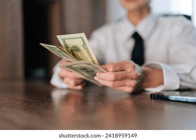 Closeup female hands of counting American currency. Closeup cropped shot of business woman counting money cash dollars bills one, five, ten, twenty and one hundred dollar banknote, slow motion. - Powered by Shutterstock