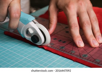 Close-up of Female Hands cutting the fabrics with round knife using ruler. HAndmade job. Tailoring and hobby concept. Making and repairing clothes. - Powered by Shutterstock