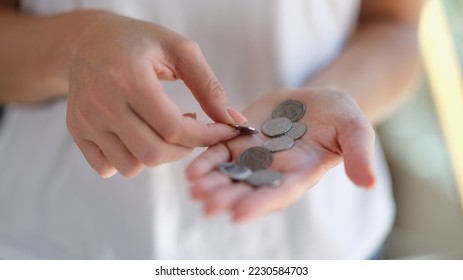 Close-up of female hands holding and counting silver coins. Saving money, poverty and small change concept