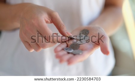 Close-up of female hands holding and counting silver coins. Saving money, poverty and small change concept