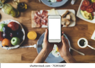 Closeup of female hands holding modern smartphone with blank screen for your text message or design, order food online concept, mock-up of mobile phone, tasty breakfast on the background - Shutterstock ID 753931807