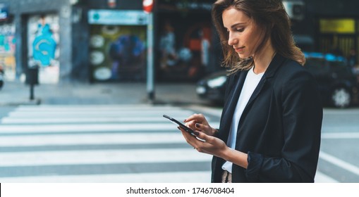 Close-up female hands holding smart phone screen on background of street crosswalk. Young businesswoman using mobile device standing on city road - Powered by Shutterstock