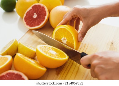 Closeup of female hands with knife slicing citrus fruits on cutting board for homemade fresh juice - Powered by Shutterstock