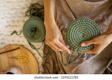 Closeup female hands knitting interior decor basket use green ribbon yarn and crochet needle. Creative woman arms enjoying needlecraft hobby or art work making comfortable cotton sewing accessories