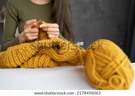 Close-up of female hands knitting wool sweater. Woman knits from thick yarn. Handmade clothes. The girl goes in for her hobbies. Knitting concept