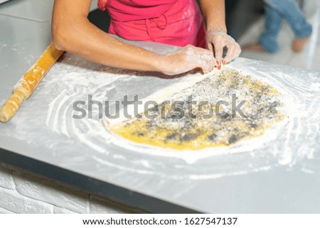 close-up. female hands make roll dough with poppy seeds and butter