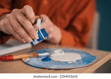 Close  up female hands palette pouring blue acrylic paint  Vacation   hobby concept  no face