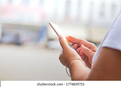 Nahaufnahme von weiblichen Händen, die mit dem Finger auf das Smartphone in der Stadt auf dem Hintergrund zeigen, Frau, die Nachrichten auf ihrem Mobiltelefon tippt
