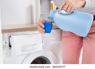 Close-up Of Female Hands Pouring Detergent In The Blue Bottle Cap