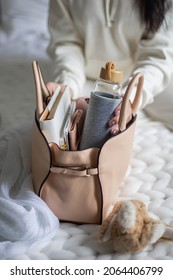 Closeup female hands putting reusable water bottle into handbag getting ready before leaving at bedroom. Active woman sticking to drinking regimen, control aqua balance enjoying healthy lifestyle - Shutterstock ID 2064406799
