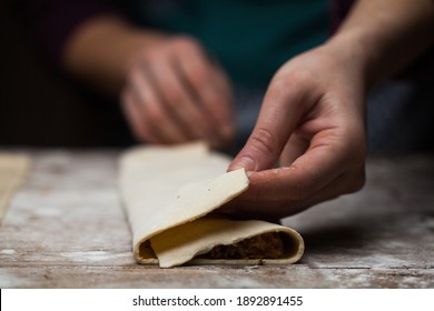 Closeup of female hands rolling pastry dessert,hand made artisan craft recipe,traditional apple strudel house made pie with organic ingredients,shallow focus on layered sheets,home preparation process