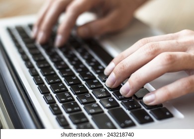 Close-up of female hands typing text on the keyboard of laptop or computer.