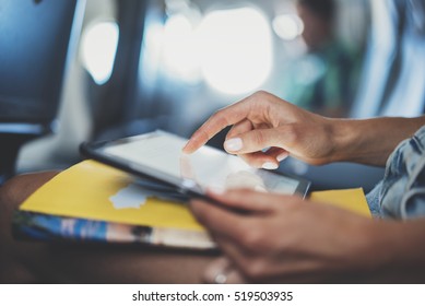 Closeup of female hands typing text information on digital tablet device while sitting at airplane, young female traveler using tablet pc while waiting her take off on aircraft, inside airplane cabin - Powered by Shutterstock