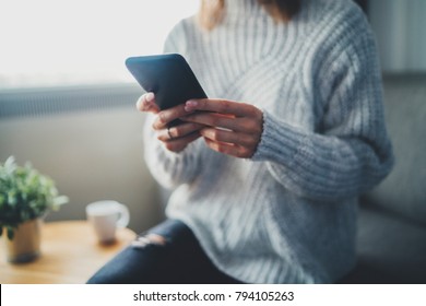 Closeup of female hands using modern smartphone device at home, focus on cellphone, social network and communication concept