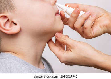 A Close-up Of Female Hands Using Nasal Spray For A Child's Runny Nose And Congestion Isolated On A White Background. Treatment Of The Disease. Rhinitis, Sinusitis, Cold, Flu. A Mother Treats Her Kid