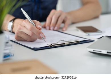 Close-up of female hands. Woman writing something sitting at her office. Signing documents