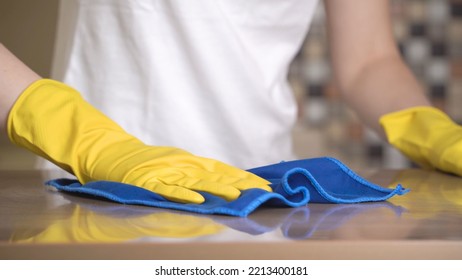 Close-up of female hands in yellow protective rubber gloves cleaning the surface of the kitchen countertop. Homework rutine. The housewife cleans the kitchen. - Shutterstock ID 2213400181