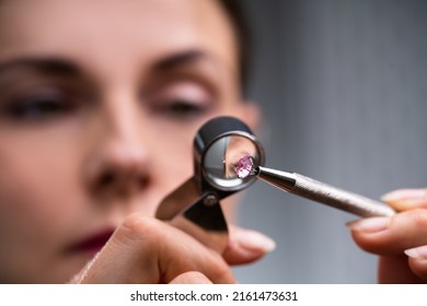 Close-up Of A Female Jeweler's Hand Looking At Diamond Through Magnifying Loupe