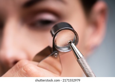 Close-up Of A Female Jeweler's Hand Looking At Diamond Through Magnifying Loupe