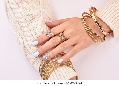 Close-up of female jewelry on hands. Beautiful hands and a knitted sweater.