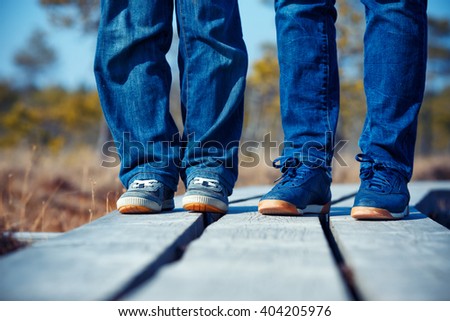 Close-up of female and kid feets in sneakers running outdoors on wooden trail, Kemeri national park, Latvia