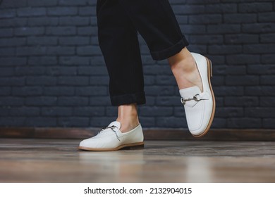 Close-up female legs in black trousers and leather beige moccasins. New spring-summer collection of women's leather shoes 2022