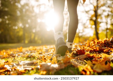 Close-up of female legs in hiking boots walks on ground with yellow-orange dry fall leaves during autumn season in park or forest. Feet walking in outdoor nature. Healthy lifestyle on leisure activity - Powered by Shutterstock