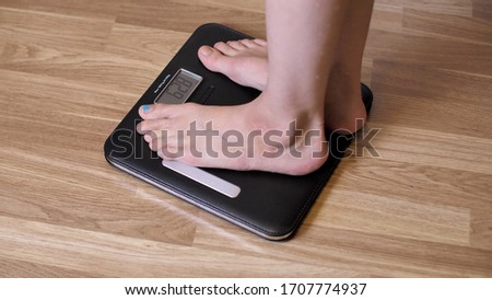 Close-up female legs stand on the scales. Thin girl or woman on scales measure weight. Human barefoot measuring weight loss or overweight during quarantine.