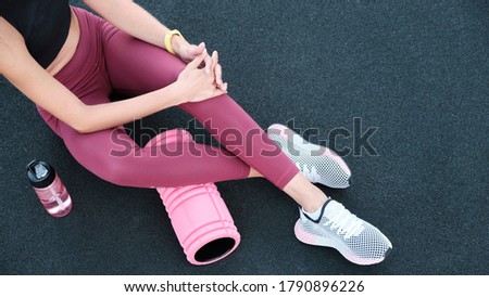 Close-up of female legs in trendy sportswear. The sportswoman sits on a blue background of the texture of the stadium cover.