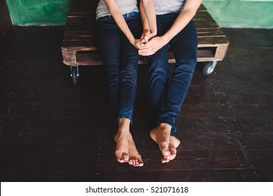 Closeup Of Female And Male Bare Feet In Jeans On Wooden Floor