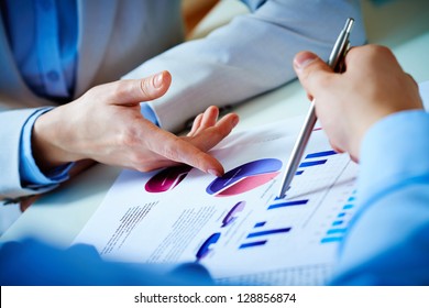 Close-up of female and male hands pointing at business document while discussing it