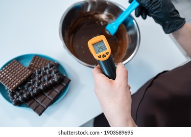 closeup of female measuring temperature of melted chocolate with pyrometer