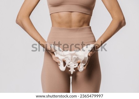 Close-up of the female pelvis in the hands of an athletic, healthy woman. Gynecology, women's healthcare and medicine and healthy body concept.