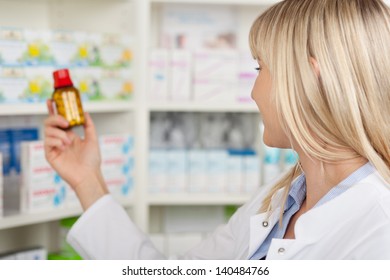 Closeup Of Female Pharmacist Holding Medicine Bottle In Pharmacy