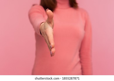 Closeup Female In Pink Sweater Stretching Hand For Handshaking, Accepting Job Offer, Partnership, Beginning Or End Of Meeting. Indoor Studio Shot Isolated On Pink Background