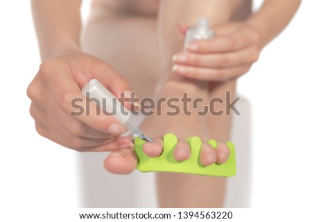 Close-up of female polishing her toe nails, isolated on white background