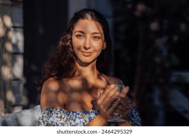 Close-up of a female portrait of a charming curly-haired young woman. An attractive brunette is smiling and her eyes closed outdoors in the park. Natural beauty. The sun and shade from the trees. - Powered by Shutterstock