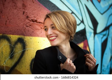 Close-up Female Portrait Of Young Smiling Girl With Short Blonde Hair Near The Wall With Graffiti. Youth Culture, Street Art Concept