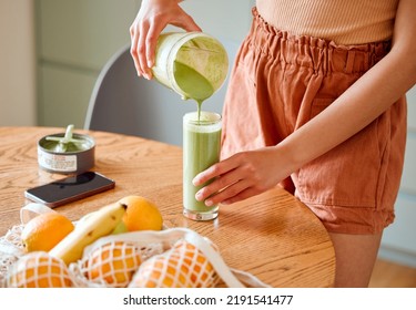 Closeup of a female pouring green healthy smoothie to detox, drinking vitamins and nutrients. Woman nutritionist having a fresh fruit juice to cleanse and provide energy for healthy lifestyle