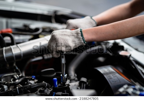 Close-up of a female repairman\'s\
hand. Car care and maintenance, hands-on car mechanic using a\
wrench to fix the car engine problem. Audit and Service\
Concepts