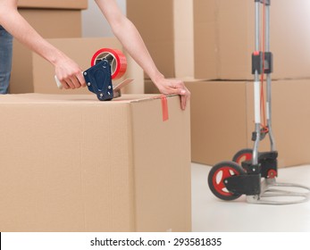 Close-up Of Female Sealing Cardboard Box With Red Duct Tape