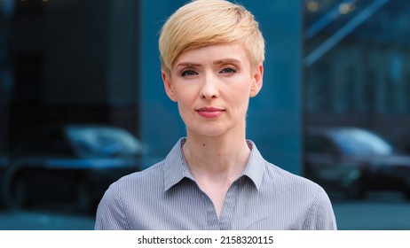 Close-up Female Serious Face Headshot Portrait Outdoors Caucasian Middle Aged Business Woman Boss Blonde Short Haired Lady Wears Formal Shirt Unhappy Calm Looking At Camera Standing Posing On Street