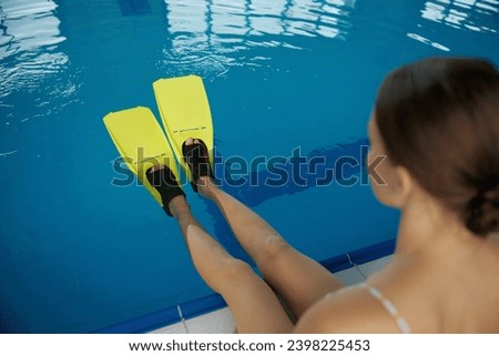 Closeup female swimmer legs wearing flippers over water surface in pool
