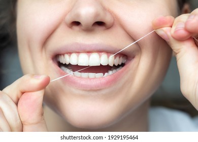 Close-up of female teeth. A Young beautiful woman flossing her teeth. Dental concept