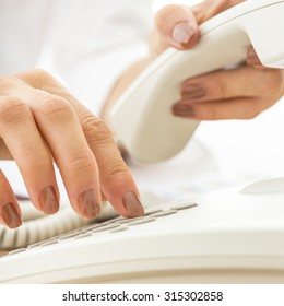 Closeup Of Female Telephone Operator Dialing A Phone Number Making An Important Business Call On White Telephone.