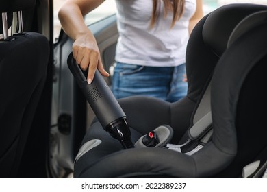 Close  up female using portable vacuum cleaner in her car  Baby ca seat cleaning  Woman vacuuming seats  Dust   dirt removal