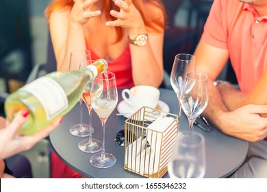 Close-up female waiter holding bottle of white champagne or prosecco for romantic couple dating on bright summer day. Girls hen-party concept. Luxury lifestyle. refreshing light alcoholic beverages